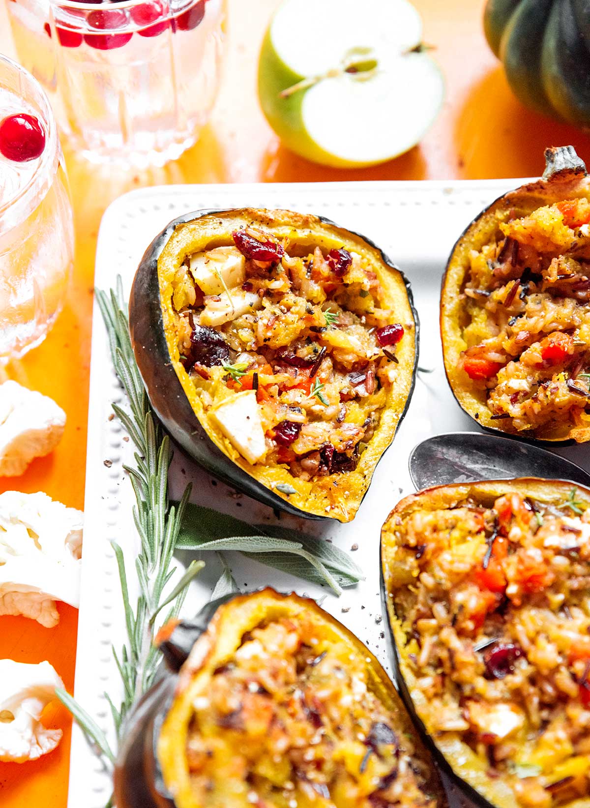 A close up view of four stuffed acorn squash halves on a white serving plate
