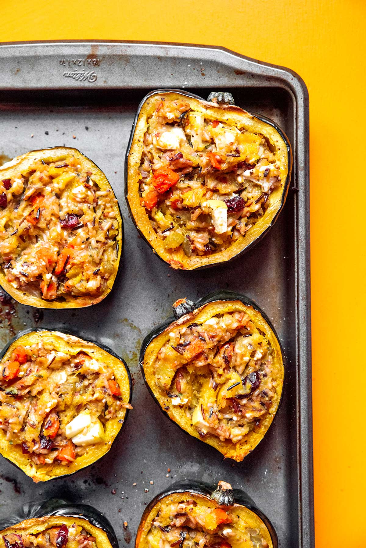 6 freshly cooked stuffed acorn squash halves laid out on a baking sheet