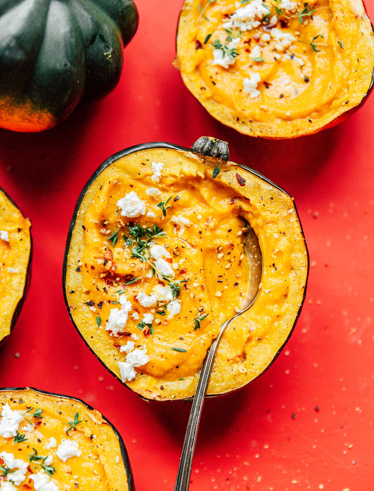 A spoon dipped into an acorn squash half filled with acorn squash soup