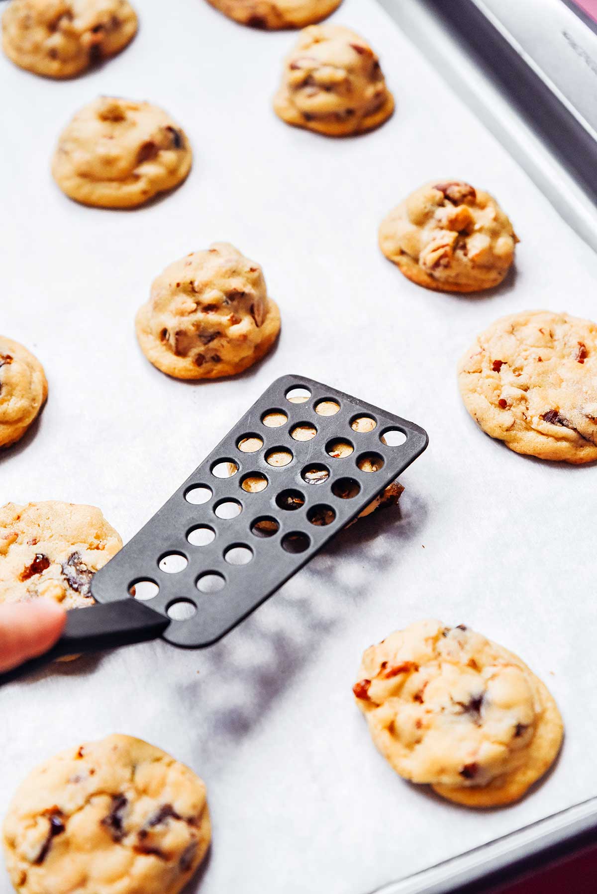 Flattening freshly baked chewy date cookies with a spatula