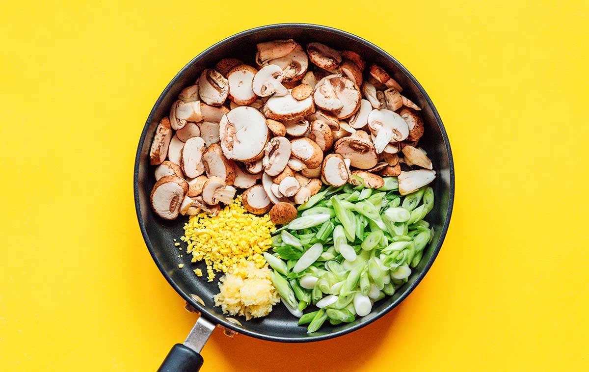 Chopped veggies in a saute pan on yellow background
