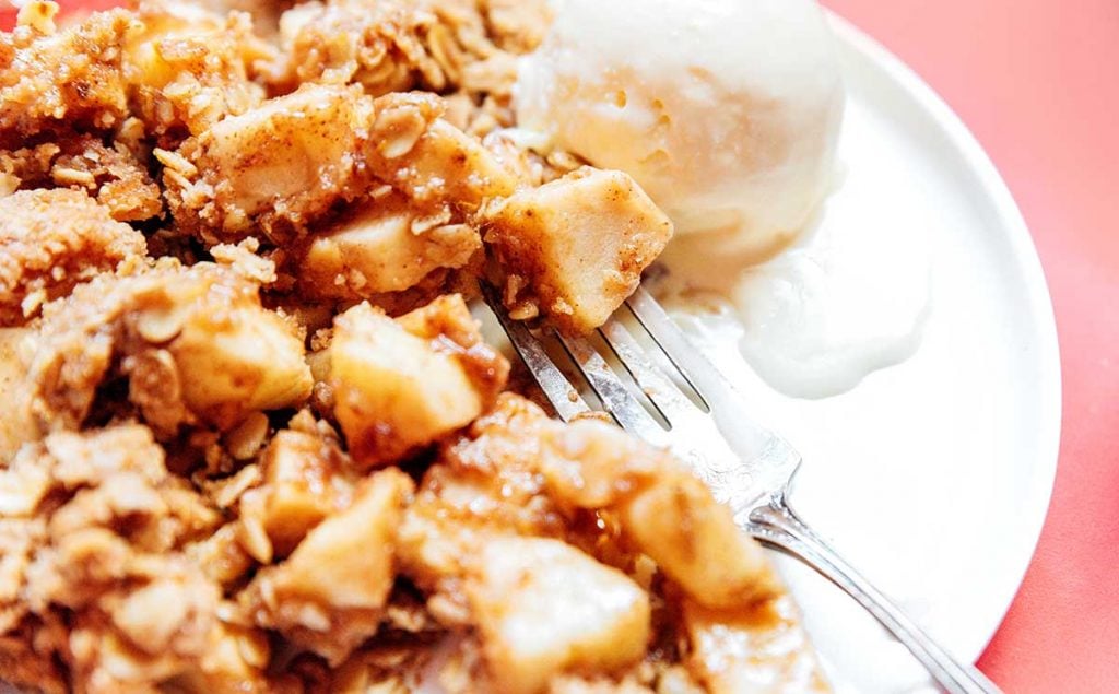 A plate filled with vegan apple crisp and a scoop of ice cream