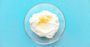 A bowl of whipped cream with a dollop of butter on top, reminiscent of the lightness in a freekeh salad, set against a calming light blue background.