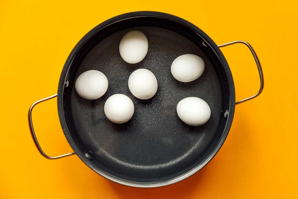 A large pot filled with water and 6 hard boiled eggs