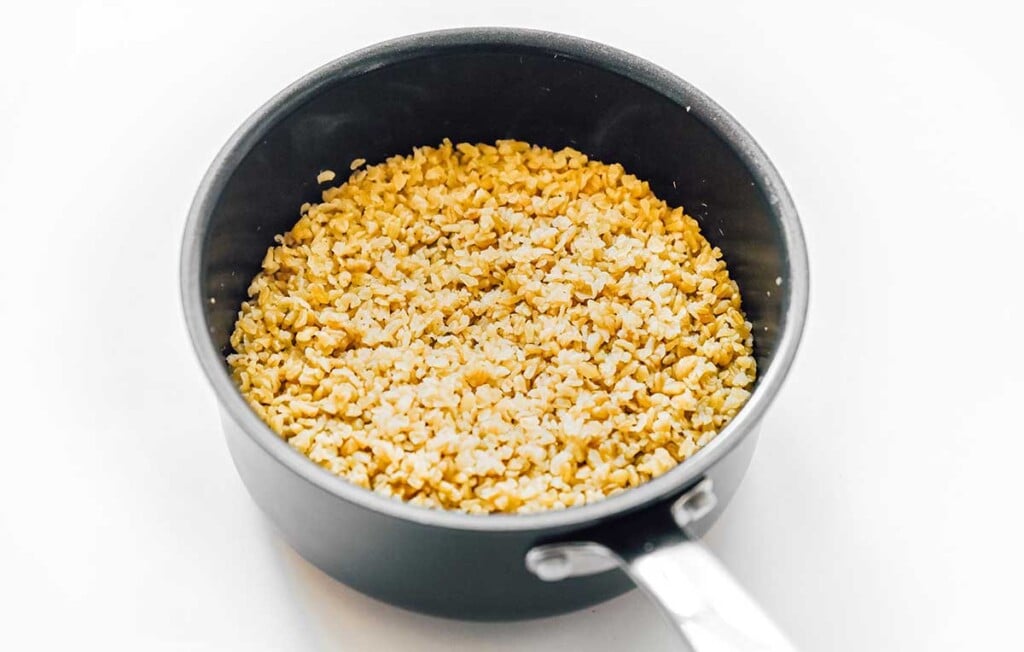 A sauce pot filled with freshly cooked and fluffed freekeh