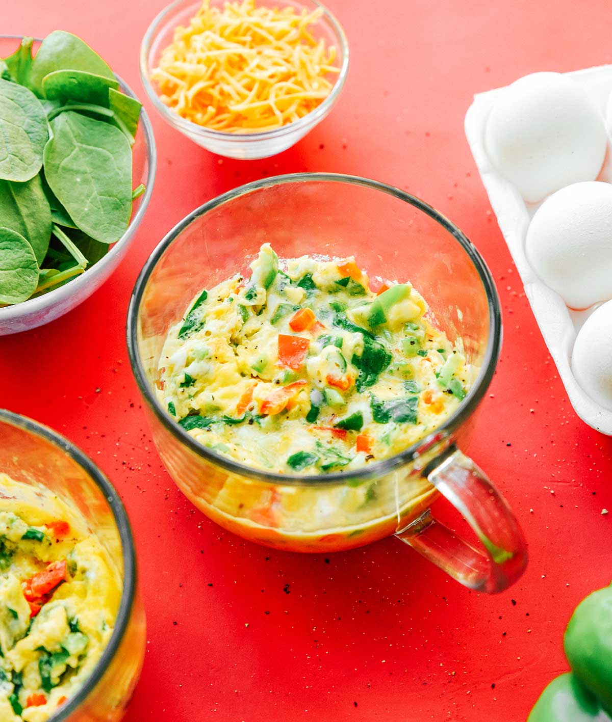A clear glass mug filled with mixed veggie mug omelette ingredients