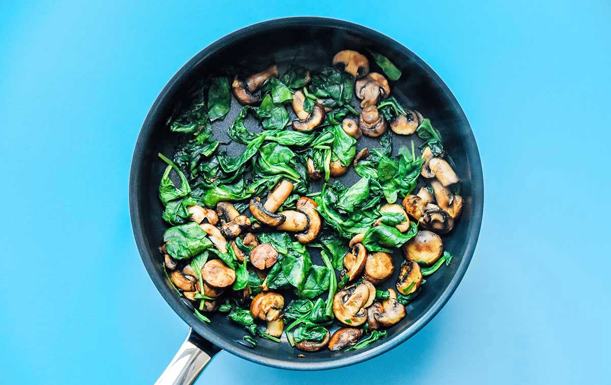 A skillet filled with sautéed mushrooms and spinach 