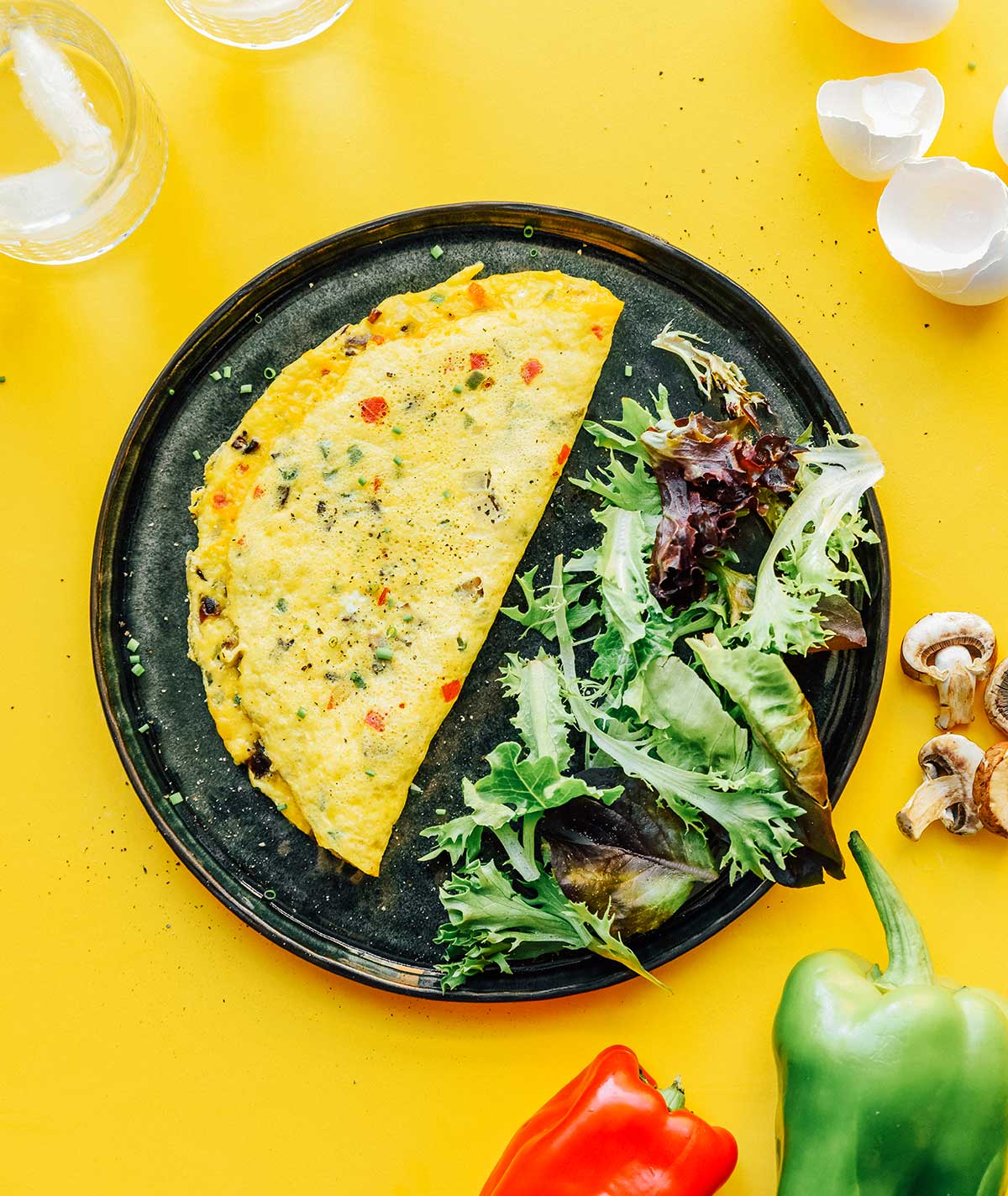 A folded veggie omelette on a plate alongside spring mix