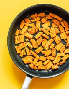 Seitan cubes cooking in a pan.