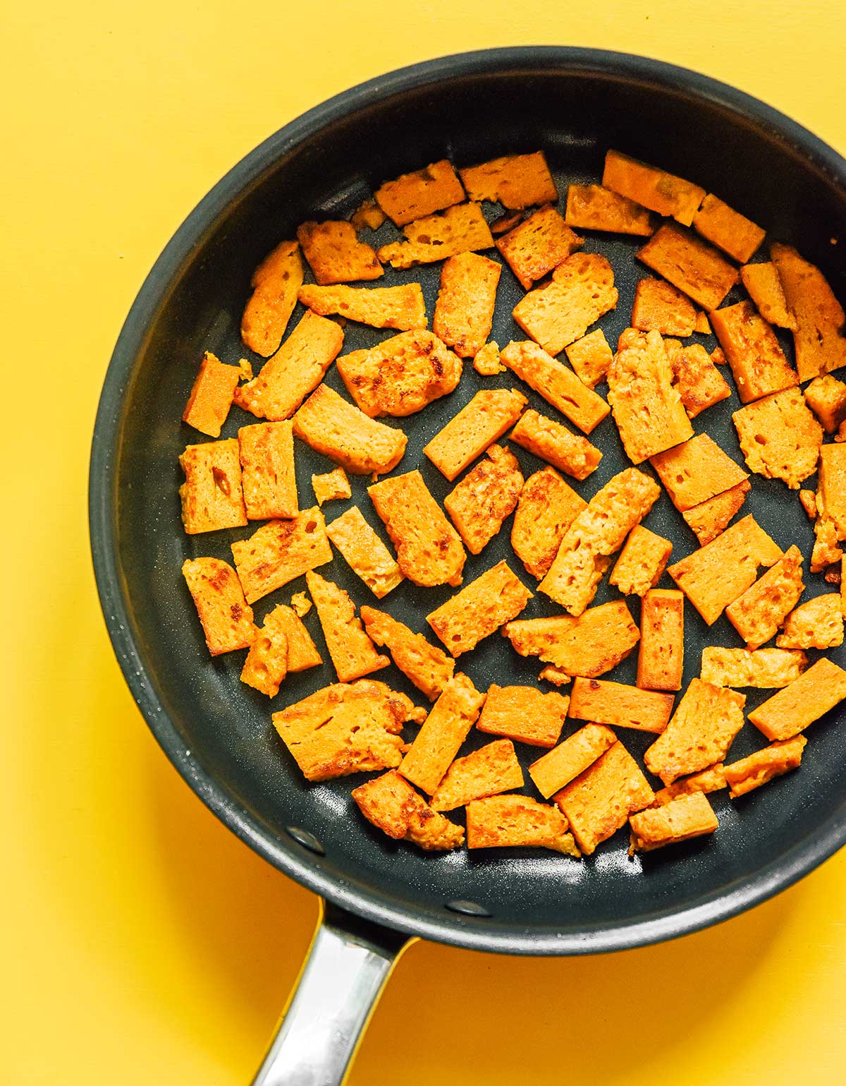 A skillet filled with an even layer of cubed, uncooked seitan 
