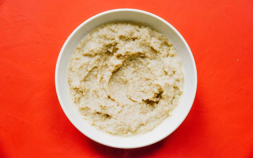 A white bowl filled with an oatmeal and water mixture