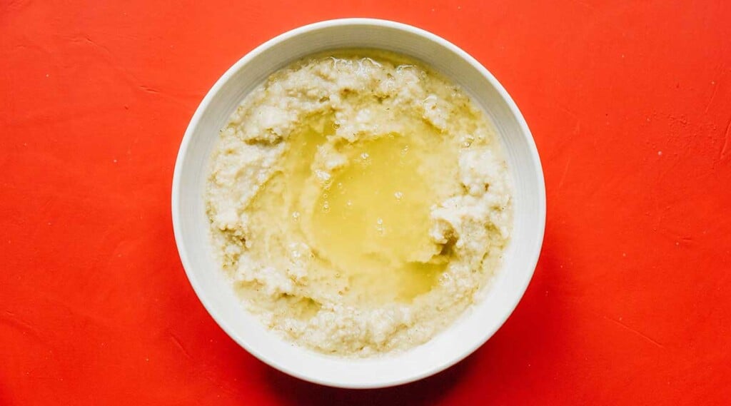 A white bowl filled with water, oatmeal, and egg whites