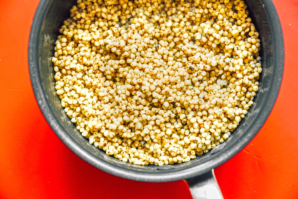 A cooking pot filled with freshly cooked and fluffed sorghum