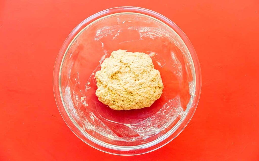 A clear glass bowl with a ball of seitan dough inside