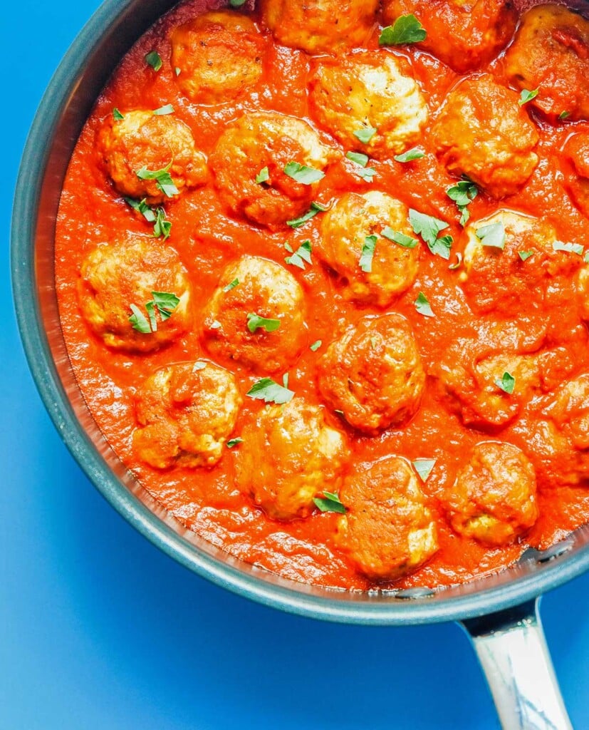 A close-up view of a skillet filled with marinara sauce and seitan meatballs