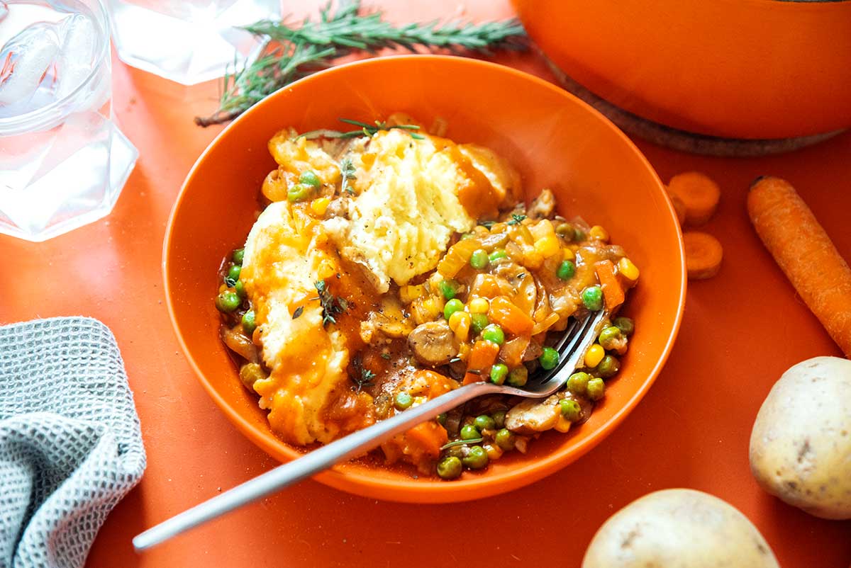 An orange bowl filled with a serving of vegetarian shepard's pie