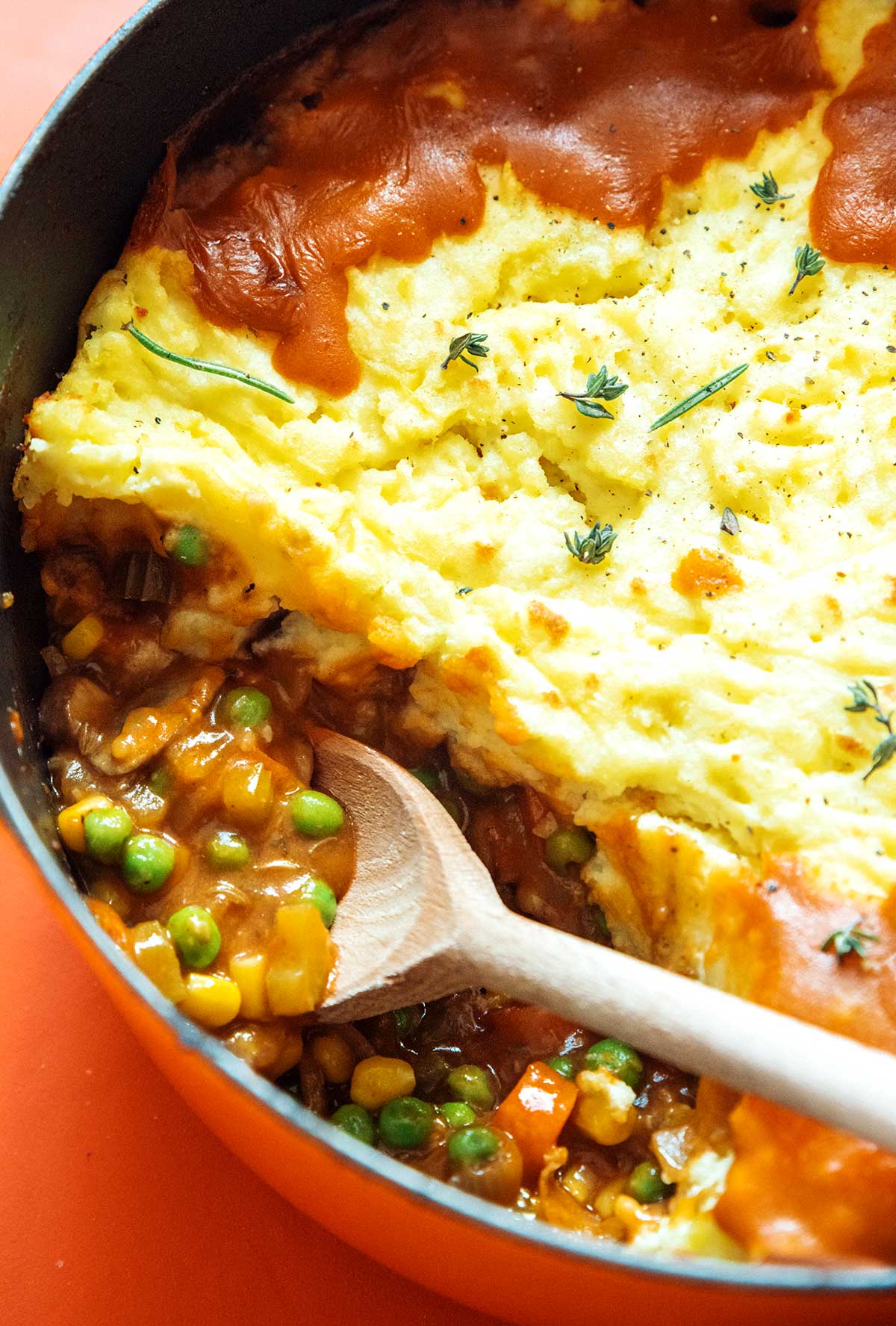 A close-up view of a wooden spoon in a pot filled with freshly cooked vegetarian shepard's pie