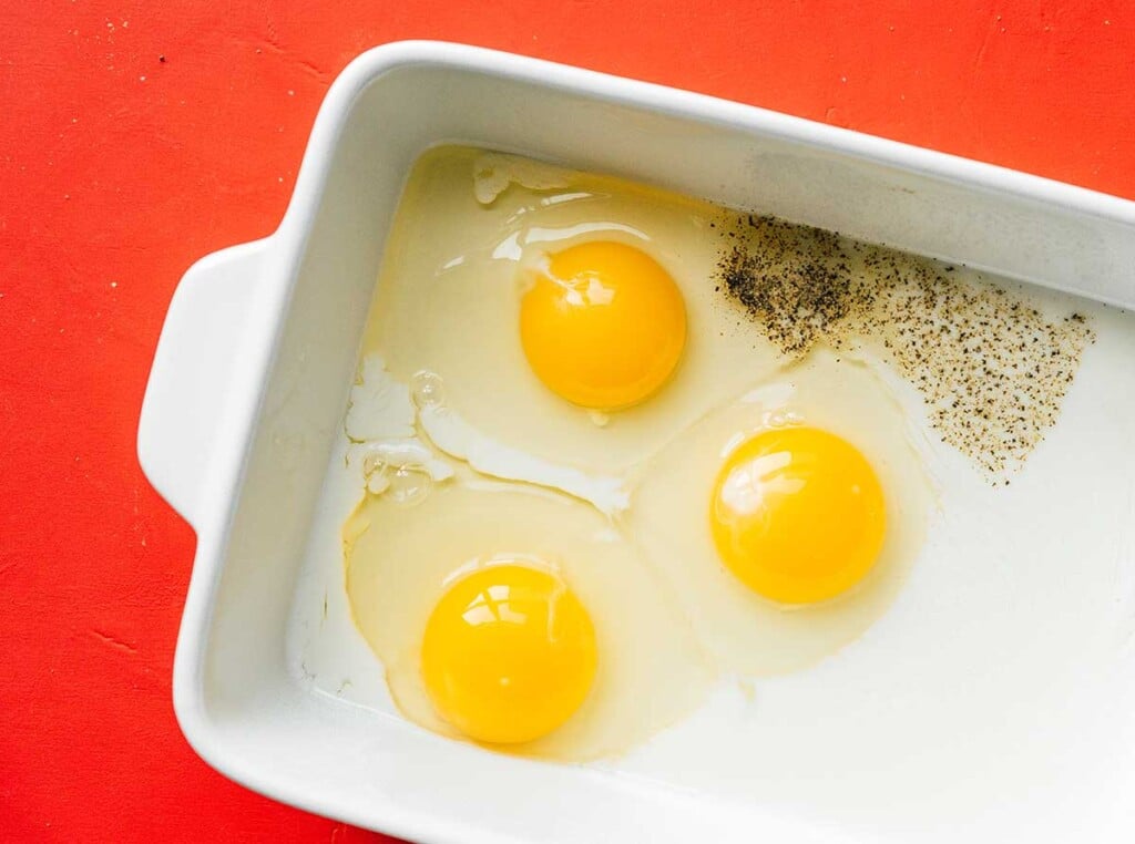 A casserole dish filled with eggs, salt, and pepper