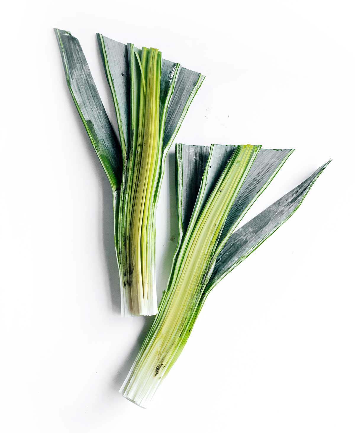 Two leek halves side by side on a white background, insides facing up