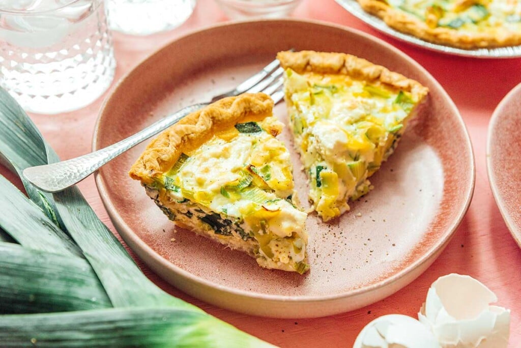 A plate filled with two thick pieces of goat cheese and leek quiche