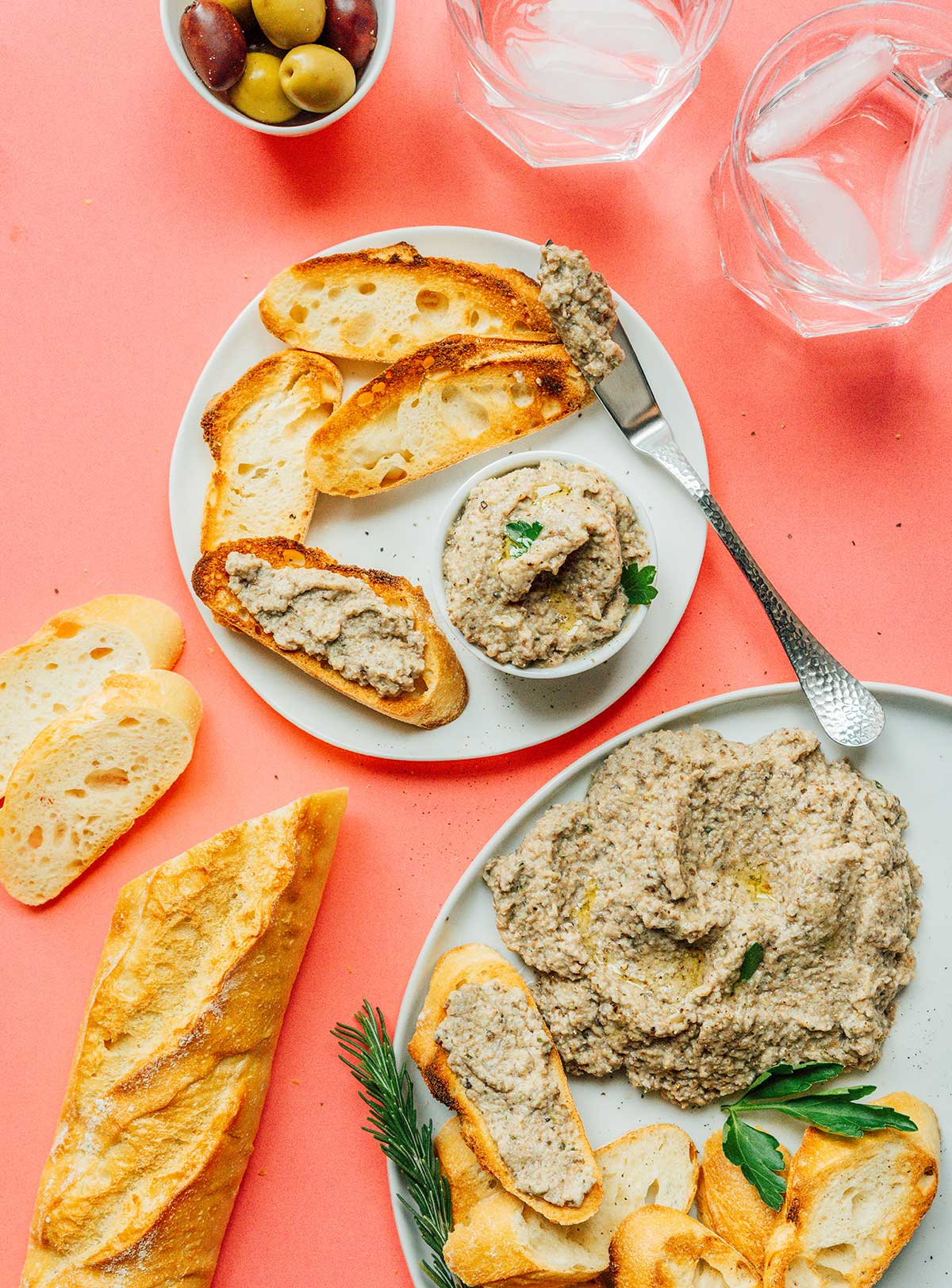 A small bowl of mushroom pâté on a white plate with slices of French bread