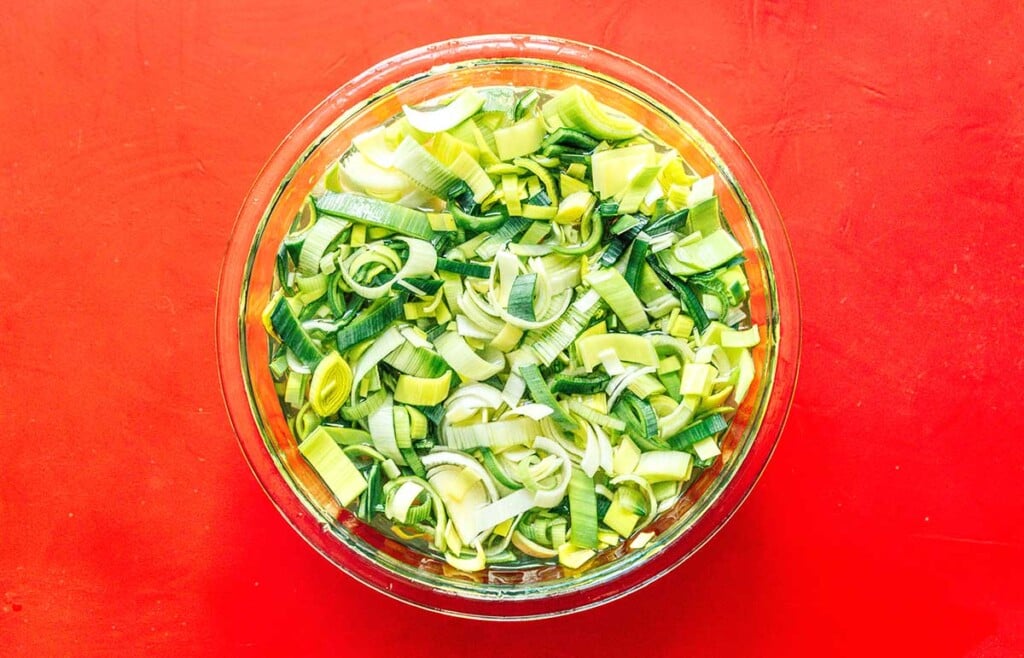 A clear glass bowl filled with sliced leeks