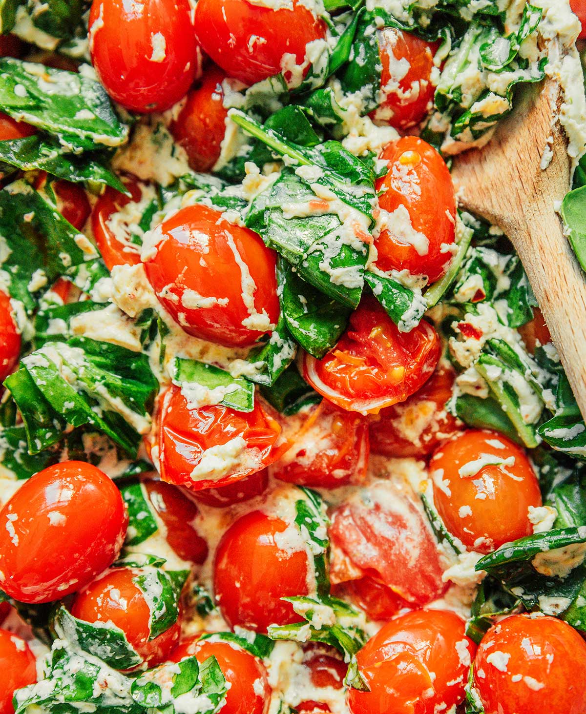 A close-up view detailing the texture and creaminess of the stirred tomato, cheese, and spinach mixture