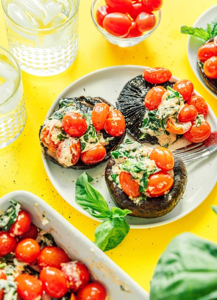 Three roasted tomato and goat cheese stuffed mushrooms on a white plate