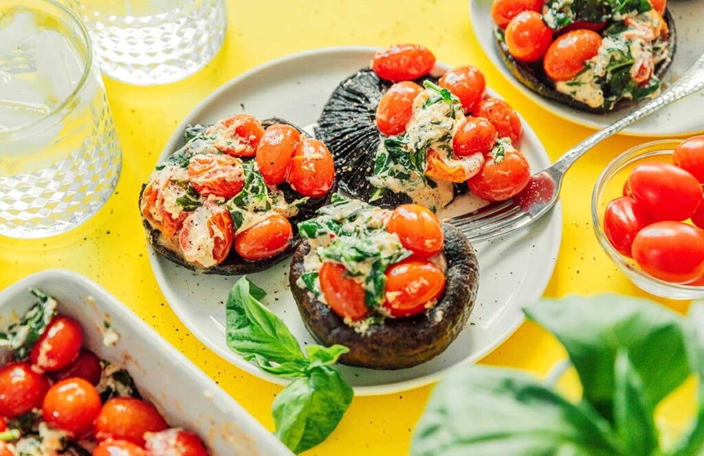 Three roasted tomato and goat cheese stuffed mushrooms on a white plate