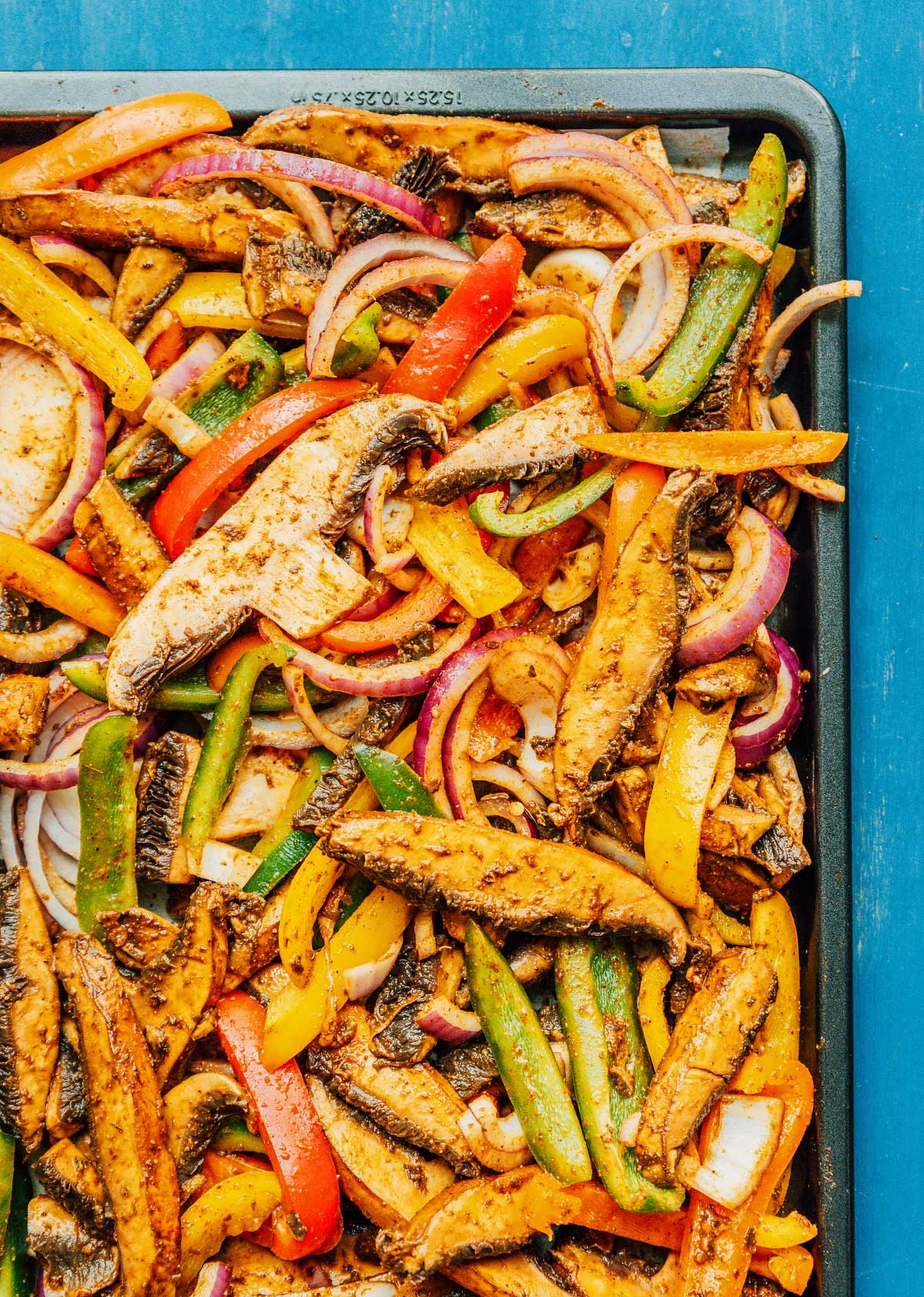 A baking sheet topped with marinated mushrooms and veggies