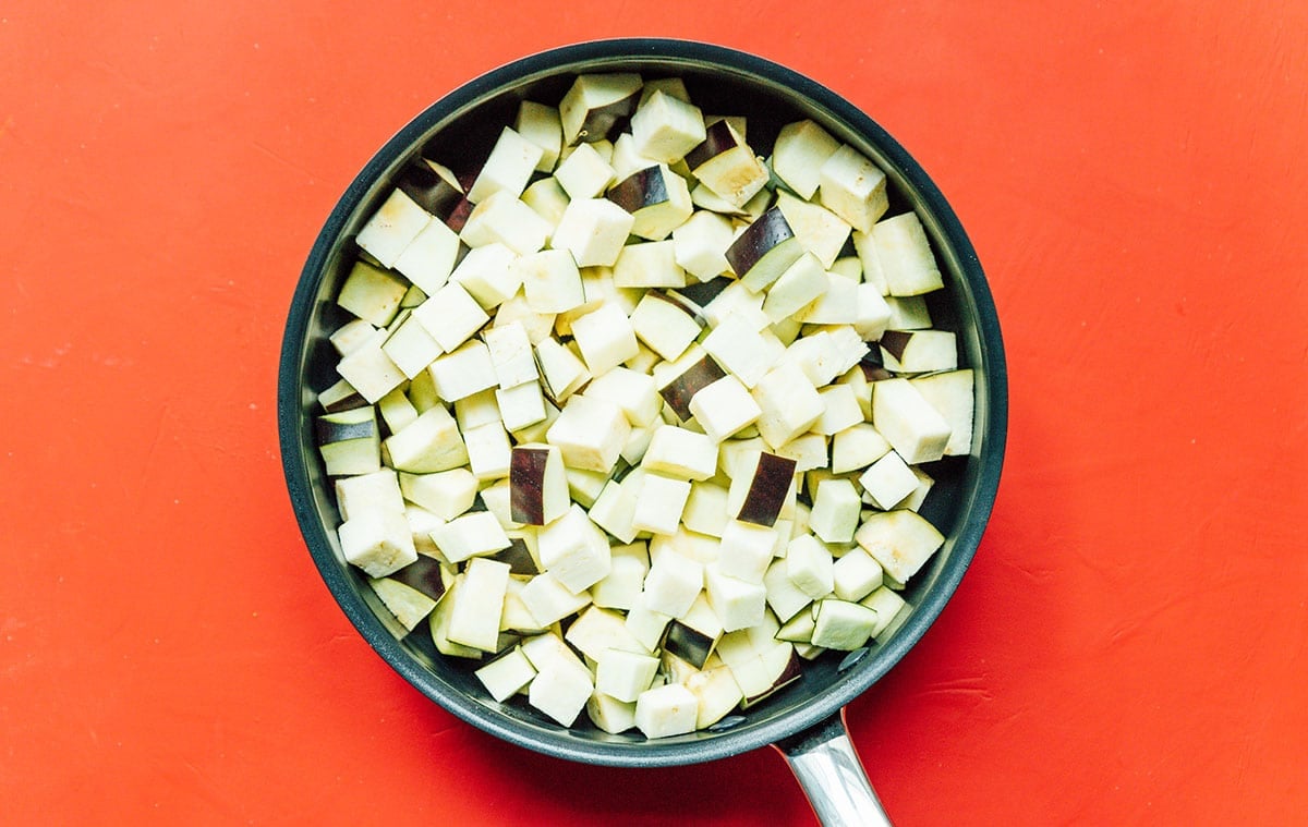 A skillet filled with uncooked, diced eggplant
