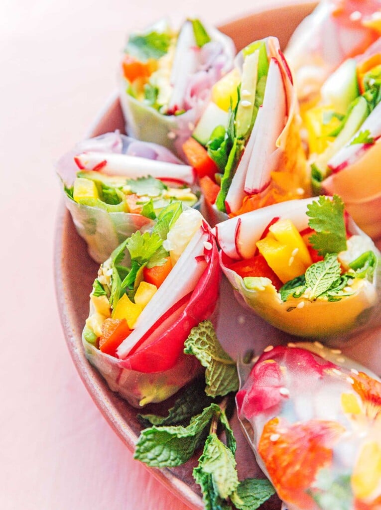 About seven flower spring rolls arranged in a pink bowl