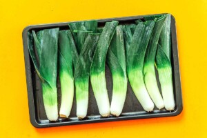 Raw leeks on a baking sheet.