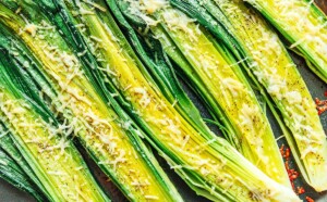 Roasted leeks, halved and seasoned with black pepper, are beautifully complemented by a sprinkle of parmesan cheese as they roast to perfection on a baking sheet.