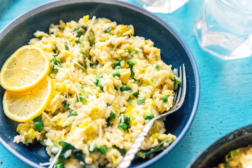 A blue bowl filled with leek risotto and topped with lemon slices