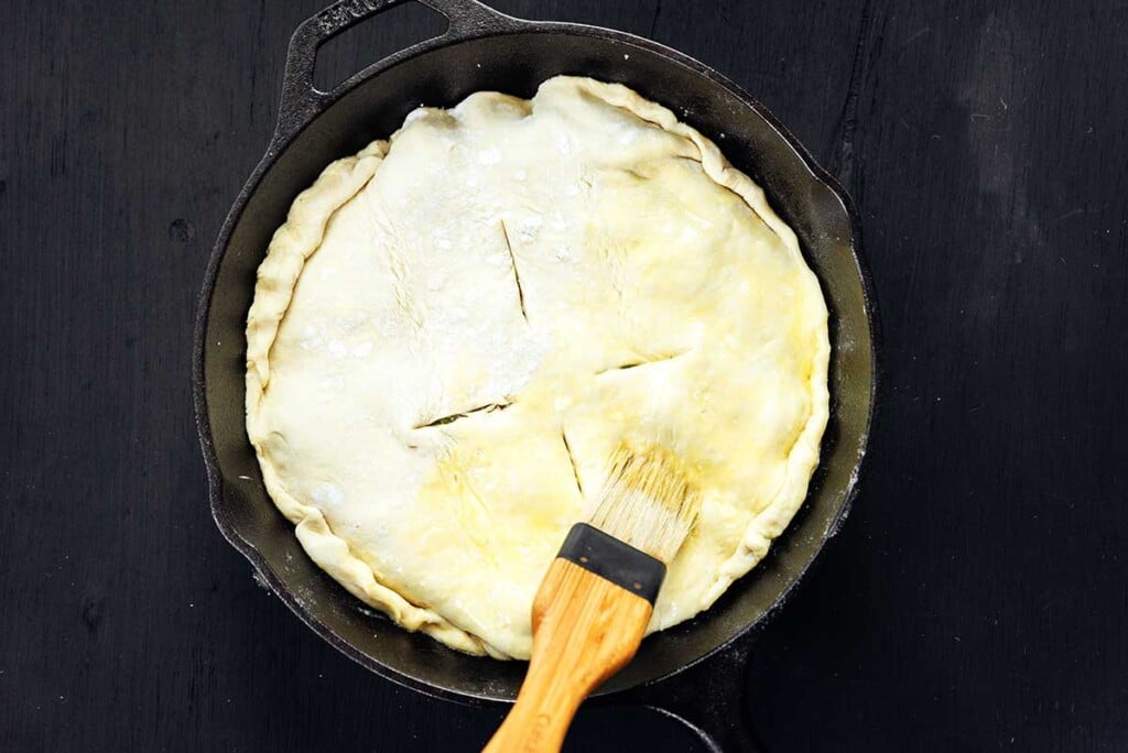 Brushing an egg wash onto the top of the leek tart puff pastry