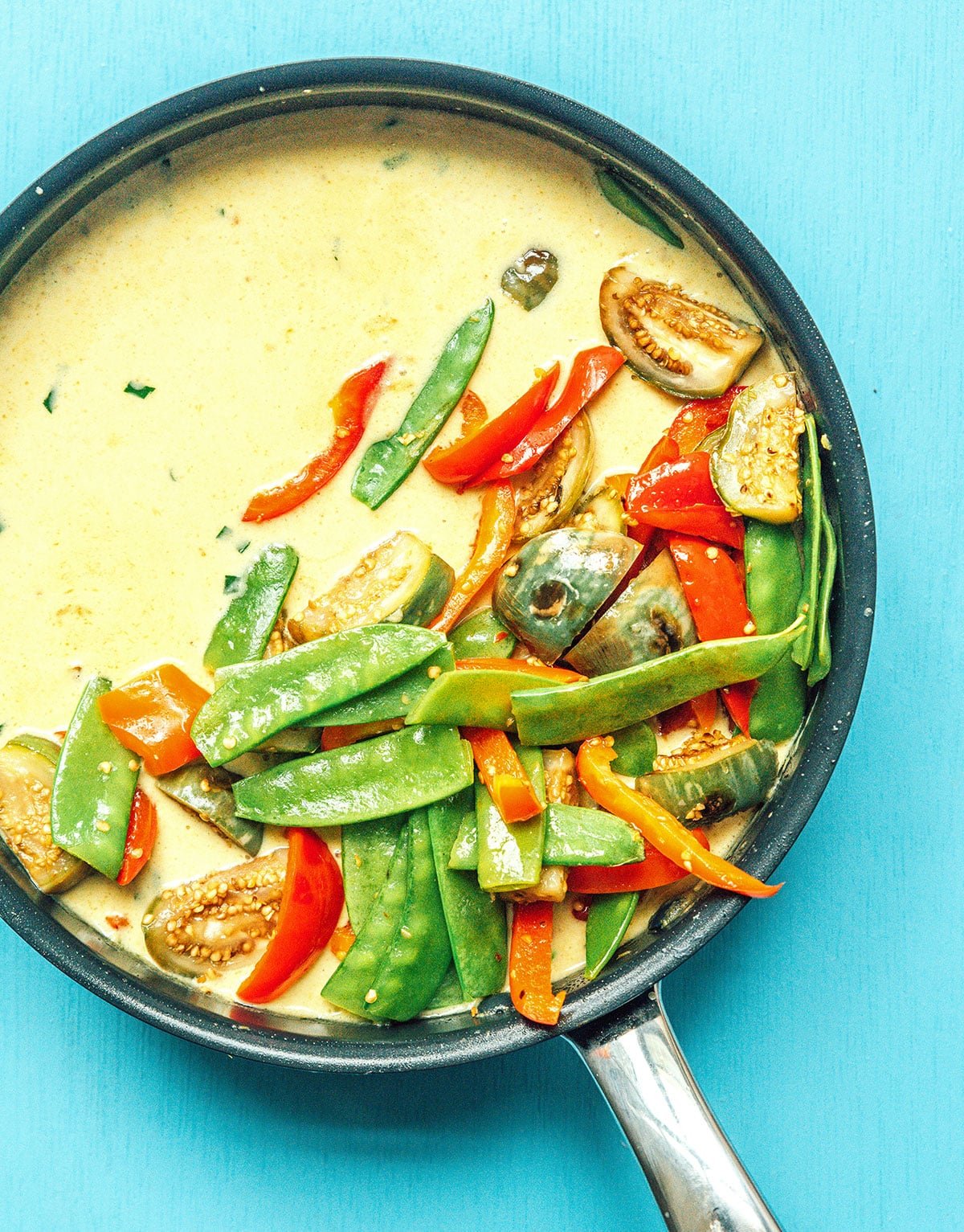 A skillet filled with vegetables and green curry sauce