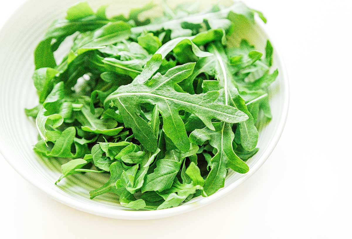 A while bowl filled with bright green arugula lettuce
