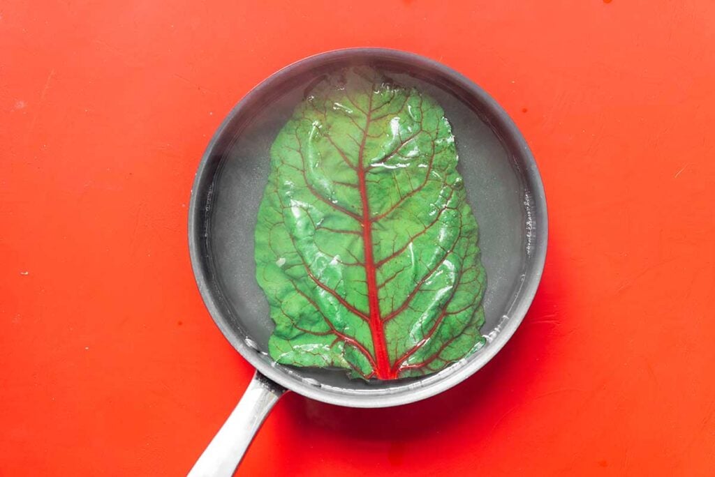 A chard leaf boiling in a pan of hot water