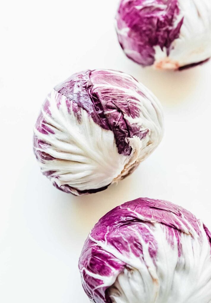 Three heads of purple radicchio lettuce on a white background