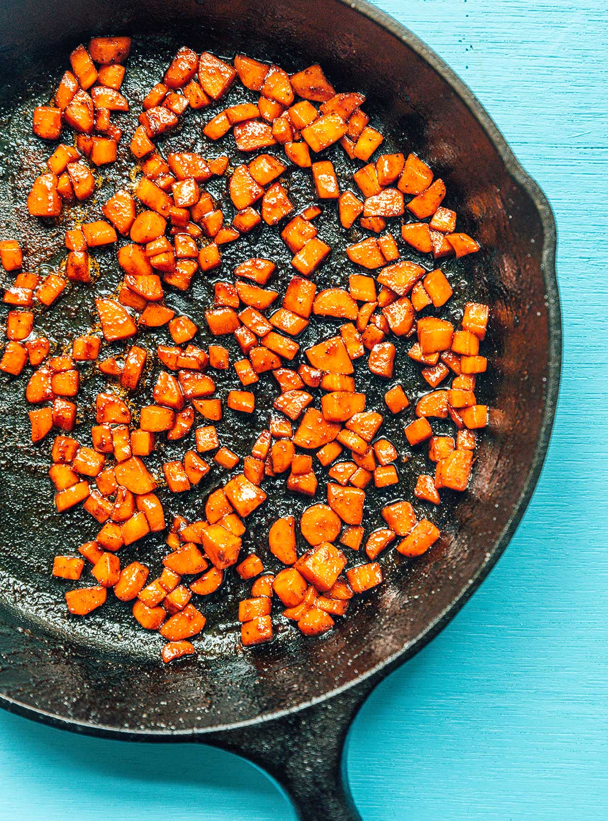 Carrot and brown sugar bacon bits cooking in a cast iron skillet