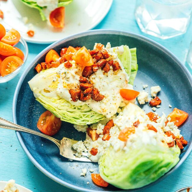 Wedge salad on a blue plate with vegan bacon bits.