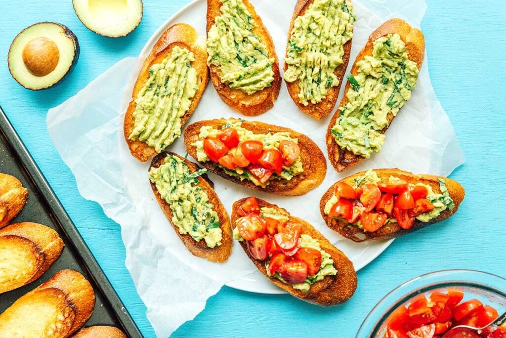 A plate filled with 8 sliced of avocado toast and avocado and tomato bruschetta 
