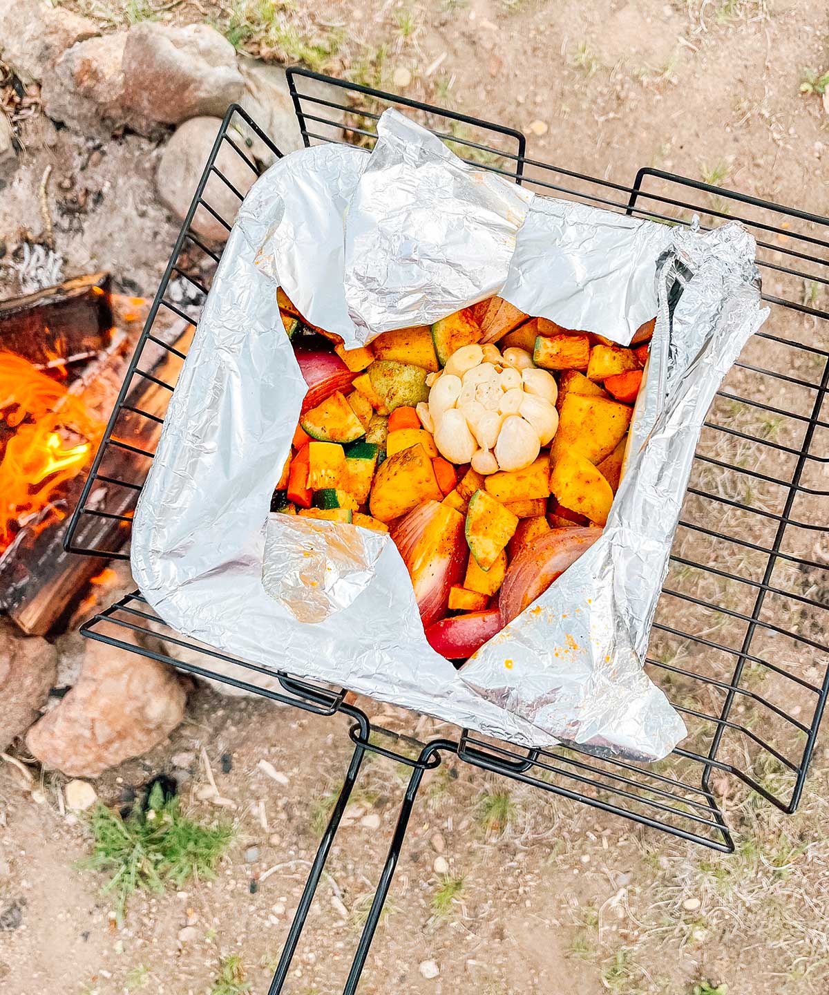 Cooking a tray of campfire roasted veggies over a campfire