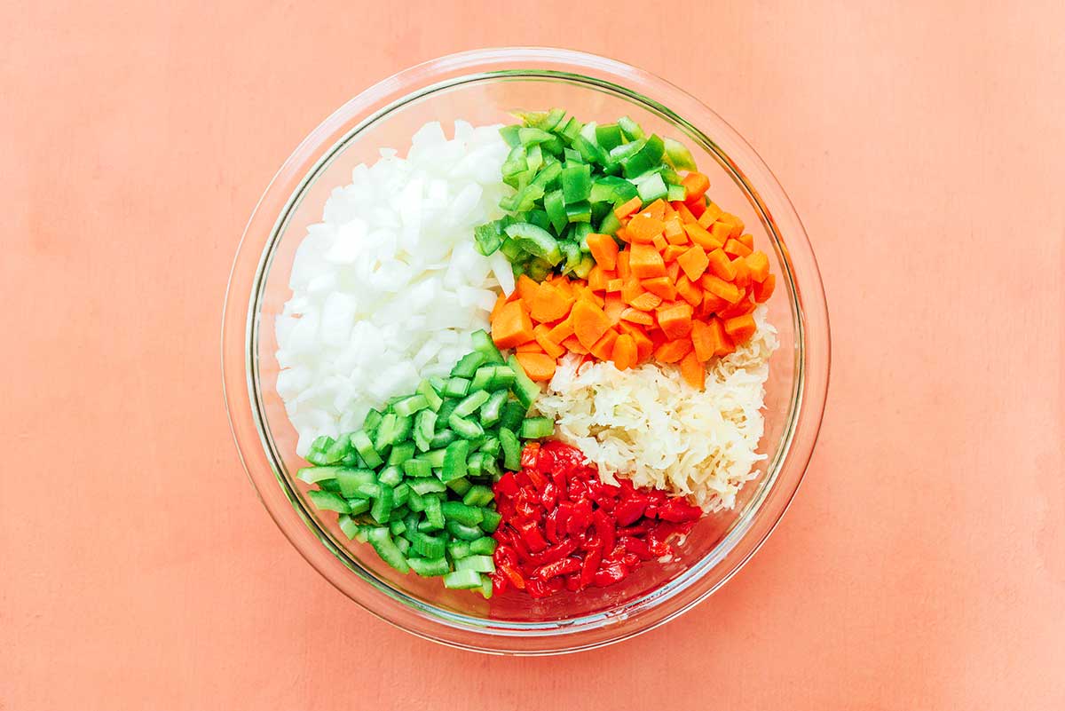 A clear glass bowl filled with prepped and diced sauerkraut salad ingredients