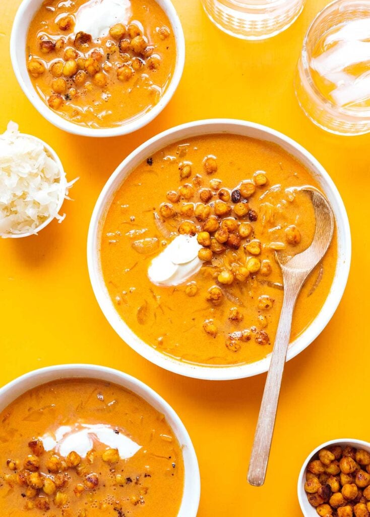 A white bowl filled with sauerkraut soup and topped with roasted chickpeas and crème fraîche