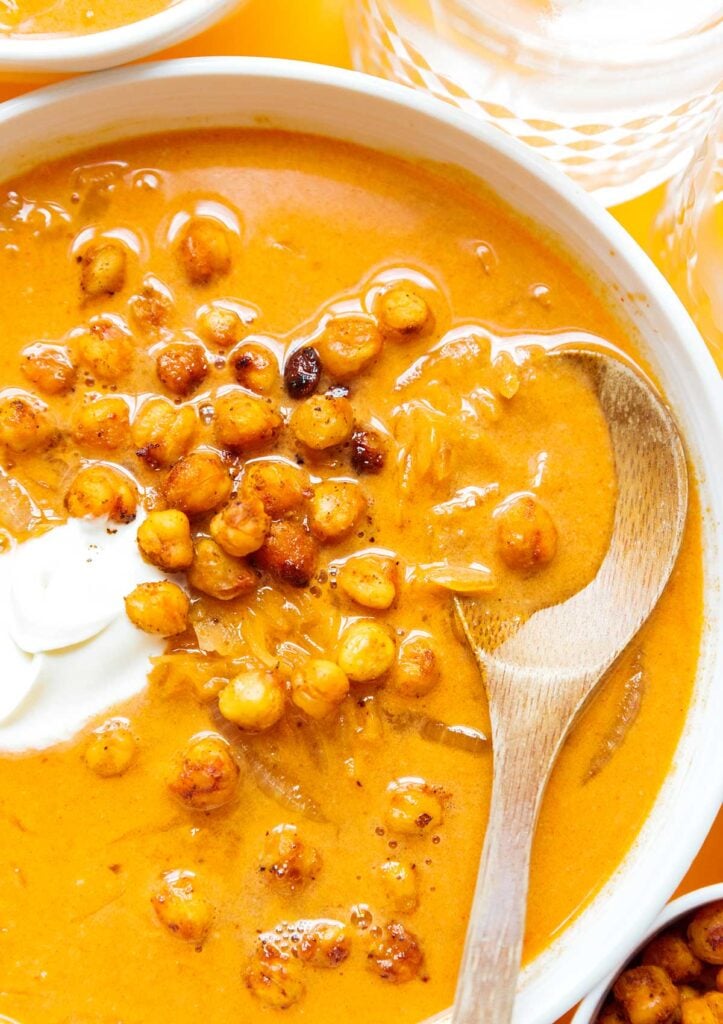 A close up view detailing the texture of sauerkraut soup topped with roasted chickpeas and crème fraîche