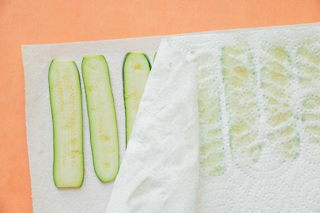 Zucchini slices lined up on paper towels to collect excess moisture 