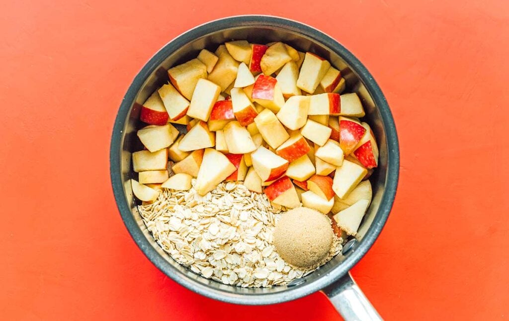 A pot filled with diced apples, rolled oats, and brown sugar