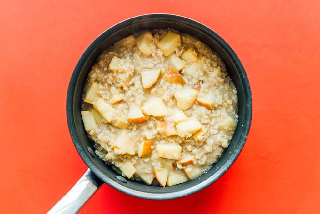A pot filled with cooked apple cinnamon oatmeal ingredients